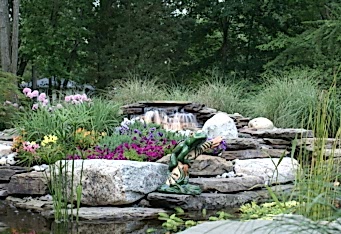 Landscape lighting lights up the waterfall in this landscaped backyard
