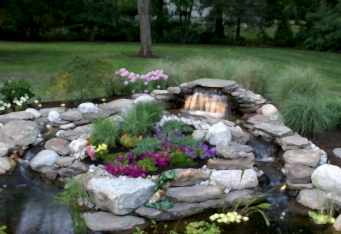 Landscape lighting lights up the waterfall in this backyard landscape