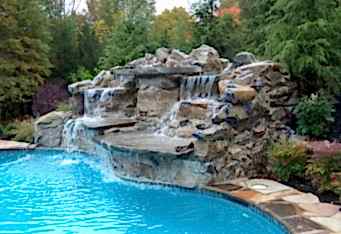 A waterfall flows into a pool in this landscape designed by GA landscape design