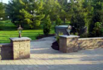Paver wall with Columns and Lighting complete the entrance to the hot tub in this landscape