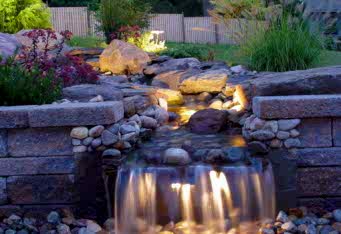 Landscape Lighting lights up a beautiful water feature completing the landscaping of this home